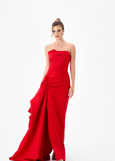Woman in a red strapless ruched gown with a dramatic skirt detail.